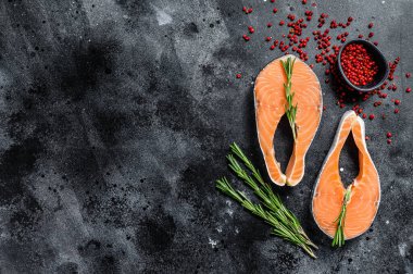 Biberiyeli ve biberiyeli iki taze çiğ somon bifteği. Siyah arka plan. Üst Manzara. Boşluğu kopyala.
