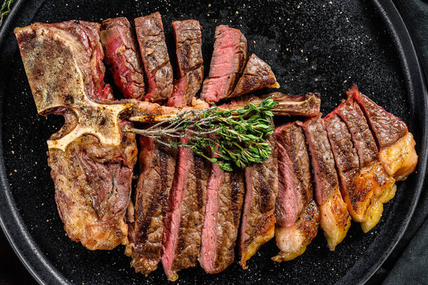 Sliced Grilled Florentine steak. T bone meat beef. Black background. Top view.