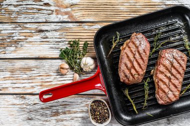 Kızartma tavasında ızgara et üst bıçaklı biftekler. Gri arka plan. Üst Manzara. Boşluğu kopyala.
