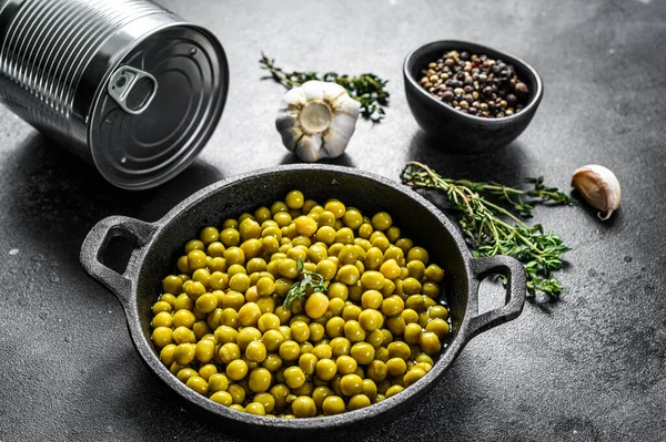 Dökme demir kasede yeşil bezelyeler. Konserve yiyecekler. Siyah arka plan. Üst görünüm.