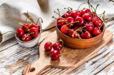 Tahta bir kasede kırmızı kirazlar. Beyaz arka plan. Üst görünüm