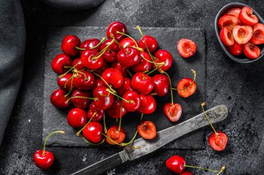 Siyah kesme tahtasındaki kirazlar. Taze kirazlar. Siyah arka plan. Üst görünüm