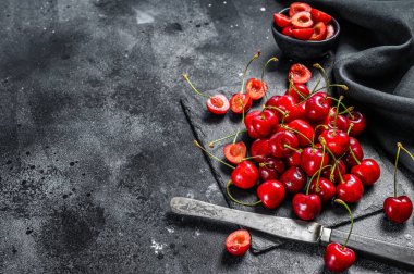 Siyah kesme tahtasındaki kirazlar. Taze kirazlar. Siyah arka plan. Üst Manzara. Boşluğu kopyala