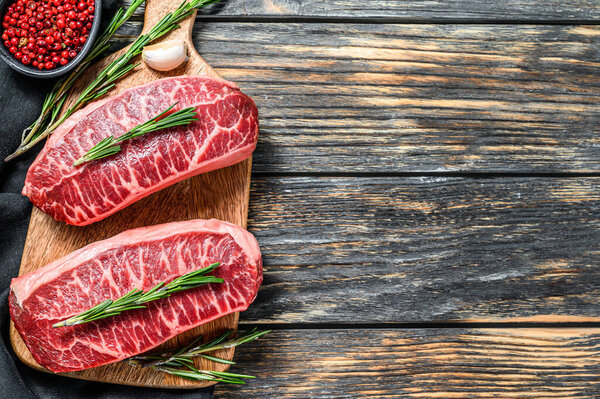 Raw marbled beef steak, top blade meat steak. Black background. Top view. Copy space.