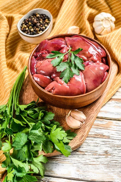 Raw chicken liver in a wooden bowl with parsley. White background. Top view — Stock Photo, Image