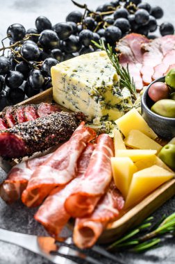 Çeşitli aperatifler, prosciutto, salam, oppa, peynir ve zeytin ile birlikte kesme tahtası. Gri arka plan. Üst görünüm.