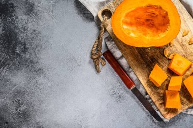 Kesme tahtasındaki çiğ balkabağı, küp şeklinde kesilmiş. Mesaj için yer var. Gri arka plan. Vejetaryen mutfağı.