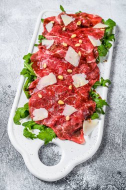 Mermer etli Carpaccio. Çiğ et, siyah Angus. Gri arka plan. Üst görünüm.