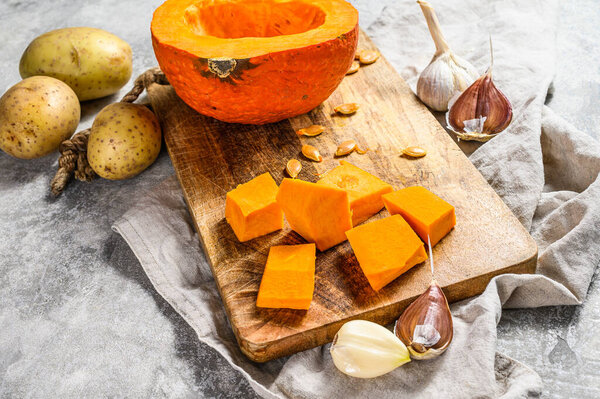 Ingredients for pumpkin soup. Gray background. Chopped Pumpkin on rustic cutting board. Tasty and healthy food. Vegan food.