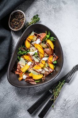 Jamon Iberico, roka, şeftali ve parmesanlı salata. Gri arka plan. Üst görünüm.