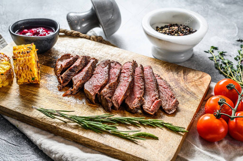 Sliced grilled black Angus marbled beef steak on a wooden chopping Board. Gray background. Top view