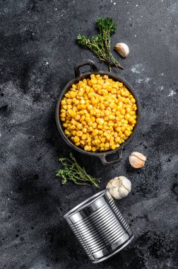 Tavada konserve mısır. Konserve yiyecekler. Siyah arka plan. Üst görünüm.