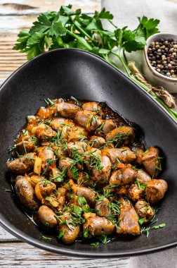 Tavuk ciğeri pişirilmiş kalpleri bir tabakta. Beyaz ahşap arka plan. Üst görünüm.