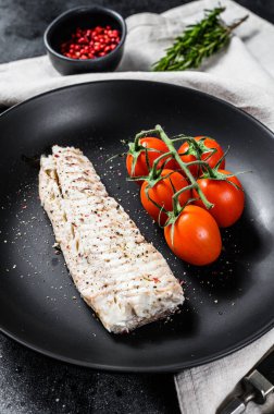 Çeri domatesli buğulanmış morina filetosu. Siyah arka plan. Üst görünüm.