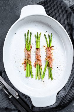 Domuz pastırmasına sarılı ızgara yeşil kuşkonmaz. Siyah arka plan. Üst görünüm.