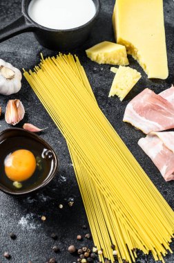 Geleneksel İtalyan Carbonara Makarnası. Pastırma, spagetti, parmesan peyniri ve pekorino peyniri, yumurta, sarımsak. Siyah arka plan. Üst görünüm.