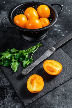 Yarı sarı kiraz domatesi dilimlenmiş. Siyah arka plan. Üst görünüm.