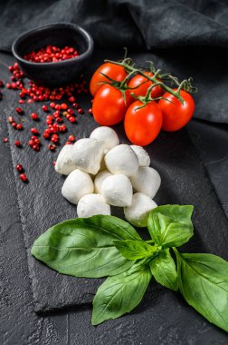 Caprese salatası, mini mozzarella peyniri, fesleğen yaprağı ve vişneli domates. Siyah arka plan. en üstteki görünüm.