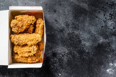 Pakette kızarmış tavuk kanadı var. Siyah arka plan. Üst Manzara. Boşluğu kopyala.