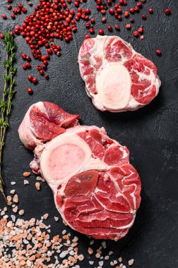 Çiğ taze ossobuco con ve şifalı otlar. Osso Buco eti. Siyah arka plan. Üst görünüm.