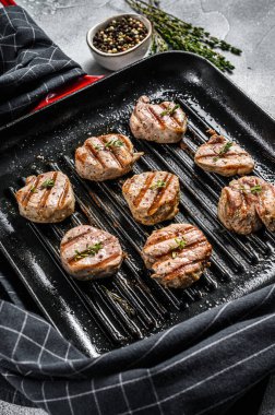 Tavada taze otlarla ızgara domuz filetosu madalyonu. gri arka plan. Üst görünüm.