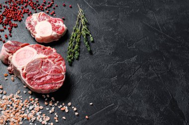 Çiğ taze ossobuco con ve şifalı otlar. Osso Buco eti. Siyah arka plan. Üst Manzara. Boşluğu kopyala.