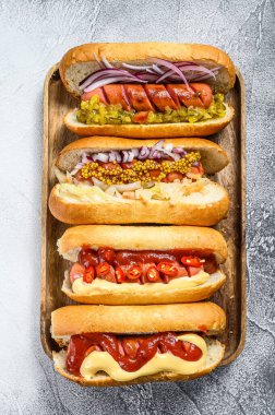 Tepside çeşitli malzemelerle dolu sosisliler. Domuz ve sığır etli sosisli nefis sosisler. Beyaz arka plan. Üst görünüm