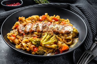 Udon eriştesi ve sebzeli ızgara ördek göğsü. Siyah arka plan. Üst görünüm.