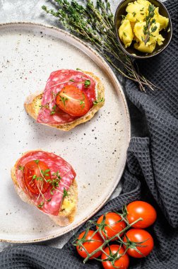 Salam soslu kanepeler, vişneli domatesler ve baget ekmekli mikro yeşiller. gri arka plan. en üstteki görünüm.