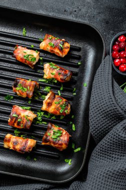 Domuz pastırmasına sarılmış kızarmış tavuk göğsü. Siyah arka plan. Üst görünüm