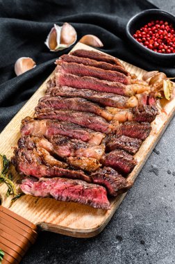 Dilimlenmiş kaburga bifteği, orta pişmiş. Siyah arka plan. Üst Manzara. Boşluğu kopyala.