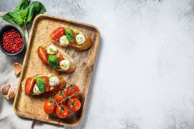 Domatesli sandviç, mozarella peyniri ve fesleğen. İtalyan aperatifi, antipasto. gri arka plan. Üst Manzara. Boşluğu kopyala.