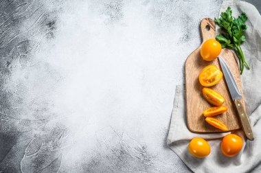 Kesme tahtasında dilimlenmiş taze sarı kiraz domatesi. Beyaz arka plan. Üst Manzara. Boşluğu kopyala.