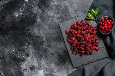 Kırmızı kurutulmuş kızılcık ve taze nane yaprakları. Organik çilek. Siyah arka plan. Üst Manzara. Boşluğu kopyala.
