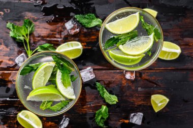Taze limonata mojito. Naneli mojito, limon ve buz. Siyah ahşap arka plan. Üst görünüm.