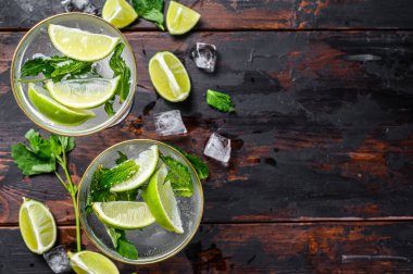 Limonlu, buzlu ve naneli mojito kokteyli. Siyah ahşap arka plan. Üst Manzara. Boşluğu kopyala.