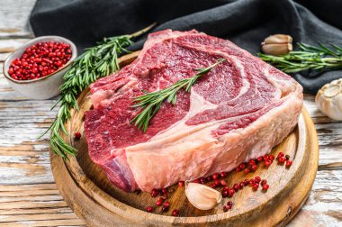 Çiğ kovboy bifteği ya da kemik üzerinde pirzola. Mermer biftek. Beyaz ahşap arka plan. Üst görünüm