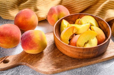 Dilimlenmiş şeftali, ahşap bir kasede organik meyve. Gri arka plan. Üst görünüm.