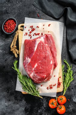 Kesme tahtasındaki çiğ sığır eti. Siyah arka plan. Üst görünüm.