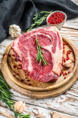 Çiğ kovboy bifteği ya da kemik üzerinde pirzola. Mermer biftek. Beyaz ahşap arka plan. Üst görünüm