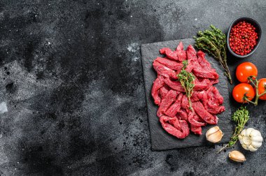 Stroganoff bifteği için ince dilimler halinde kesilmiş çiğ et. Siyah arka plan. Üst Manzara. Boşluğu kopyala.
