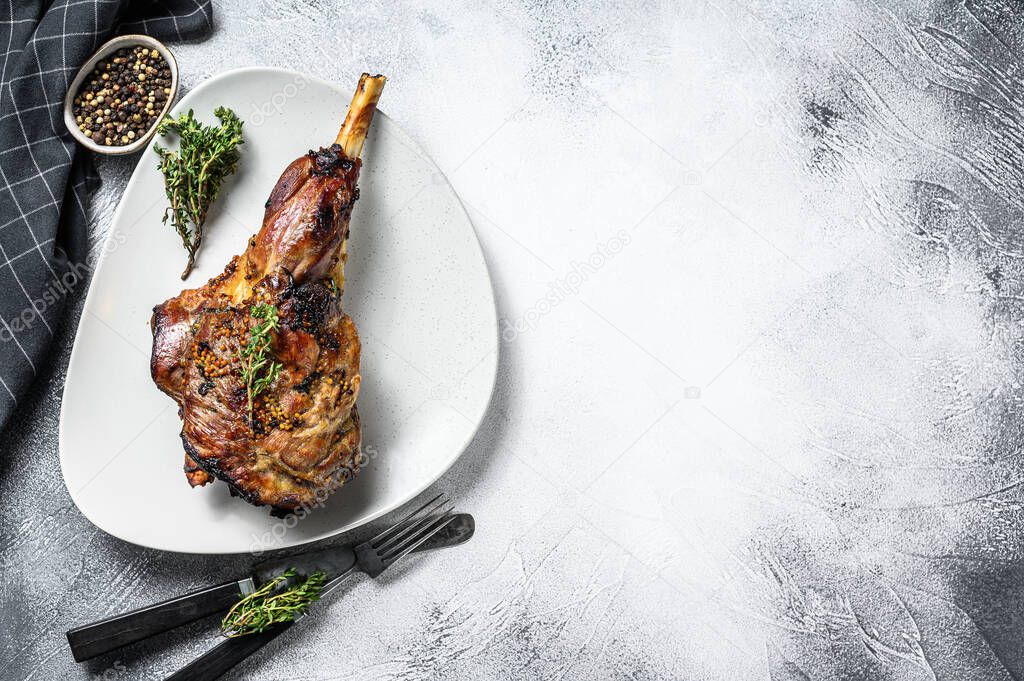 Baked goat leg with herbs. Farm meat. Gray background. Top view. Copy space.