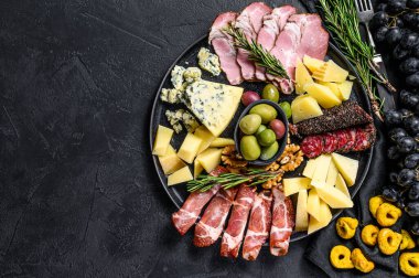 Prosciutto, jambon, peynir ve zeytinli tipik İtalyan antipasto. Siyah arka plan. Üst Manzara. Metin için boşluk.