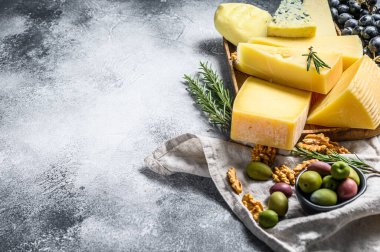 Üzüm, kraker, zeytin ve fındık ile servis edilen peynir tabağı. Çeşit çeşit lezzetli atıştırmalıklar. Gri arka plan. Üst Manzara. Metin için boşluk.