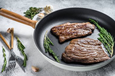 Düz ızgara demir ve tavada biftekler. Mermer sığır eti. Gri arka plan. Üst görünüm.