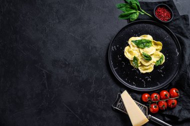 Peynirli İtalyan mantısı ve fesleğenli makarna. Siyah arka plan. Üst Manzara. Metin için boşluk.