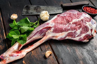 Whole raw goat leg with herbs and spices. Farm meat. Dark wooden background. Top view. clipart