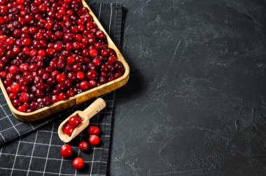 Tahta bir kasede olgun kırmızı kızılcıklar. Siyah arka plan. Üst Manzara. Metin için boşluk.