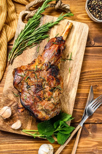 Roasted goat leg with herbs. Farm meat. Wooden background. Top view. Copy space.