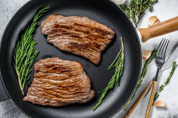 Roasted flat iron and flank steaks. Marble beef meat. Gray background. Top view.